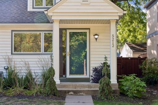 Front Entry - Covered front entry at 5212 Humboldt Ave S features a storm door, sidelight, exterior lighting, and landscaping that creates a welcoming approach.