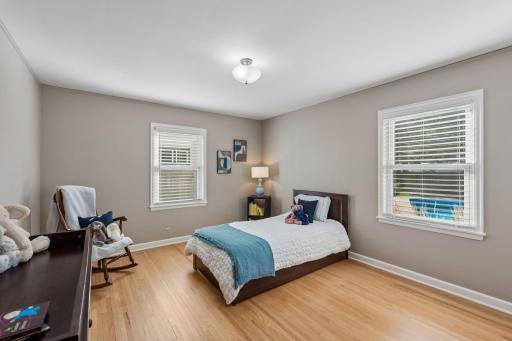 Main Floor Bedroom - Bright bedroom with hardwood floors and windows on two walls. Generous dimensions provide room for bedroom furniture, a reading chair, or additional storage.