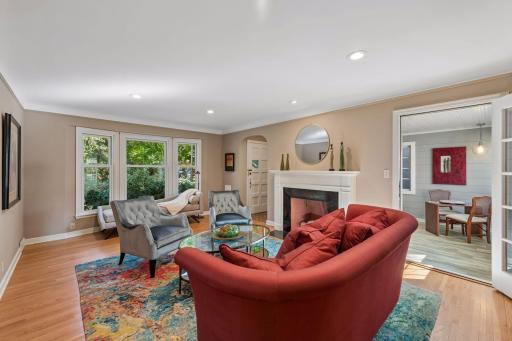 Living Room - Large windows bring natural light into the living room, while the fireplace provides a central focal point. French doors connect directly to the adjoining sunroom.
