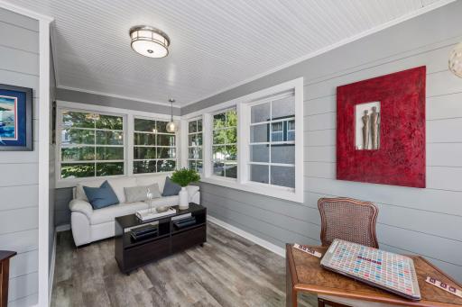 Sunroom - Bright sunroom features windows on multiple sides, horizontal wall paneling, beadboard ceiling, updated flooring, and flexible space for an office, sitting room, or creative space.