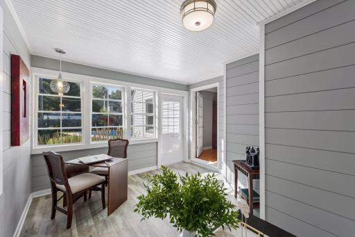 Sunroom - Another view highlights the sunroomâs abundant windows, beadboard ceiling, paneled walls, and direct connection to the living room and backyard, with views toward the pool.