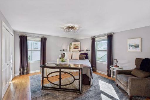 Primary Bedroom - Spacious primary upper bedroom features hardwood floors, windows on two sides, generous closet storage, and plenty of room for a sitting area.