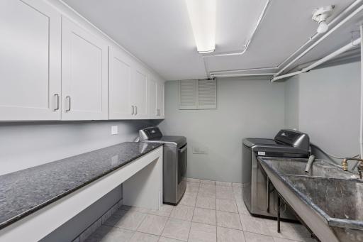Laundry Room - A second view highlights the generous cabinet and counter space, washer and dryer, utility sink, and bright overhead lighting in the lower-level laundry area.