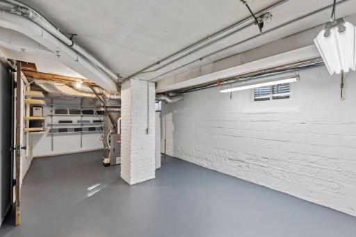 Utility & Storage Room - Clean, functional lower-level utility space offers room for storage and workshop use, with painted walls and floor, shelving, and convenient access to mechanical systems.