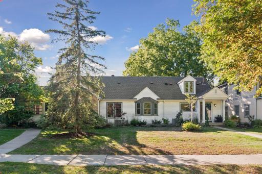 Front Exterior - Full front view highlights the homeâs broad footprint, mature trees, landscaped yard, dormer window, bay window, and welcoming covered entry.