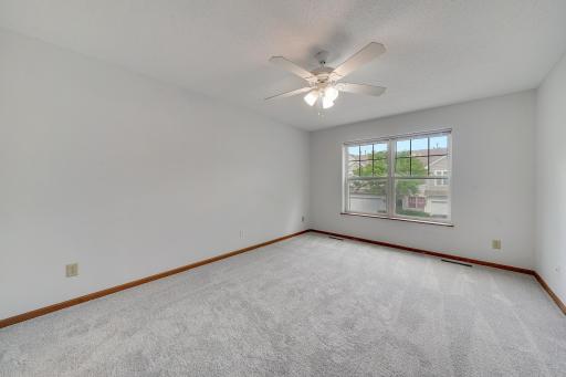 A secondary non-staged view of this primary bedroom shows the natural light pouring in and how expansive the space really is.