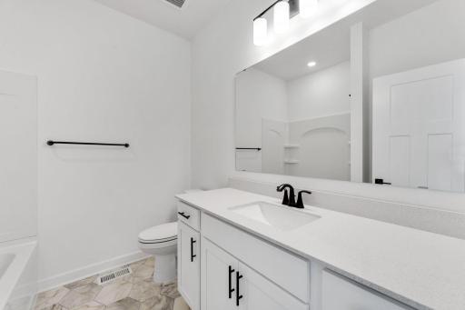 (Photo of a similar home, actual finishes may vary) Situated just off the foyer, this full bathroom is easily accessed from each of the main-floor secondary bedrooms for family members or guests.