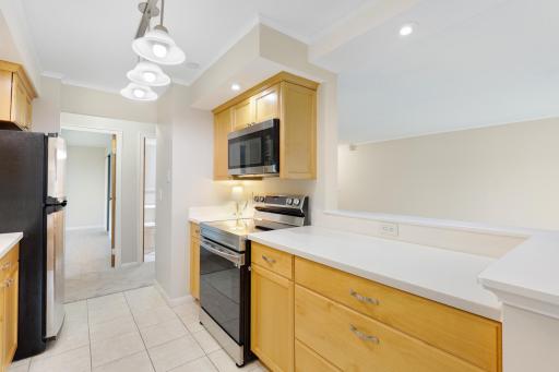 Additional kitchen view showcases abundant cabinetry and counter space, stainless steel appliances, and a convenient breakfast bar overlooking the adjoining living area for an open, connected feel.