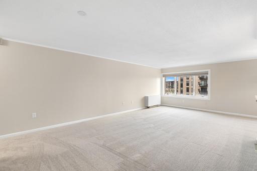 Generously sized living space with neutral finishes, soft carpeting, and a large window that brings in plenty of natural light.