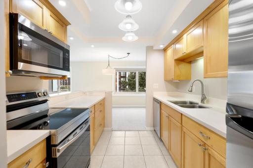 Bright, functional kitchen featuring warm wood cabinetry, ample counter space, stainless steel appliances, recessed lighting, and an open connection to the dining area.