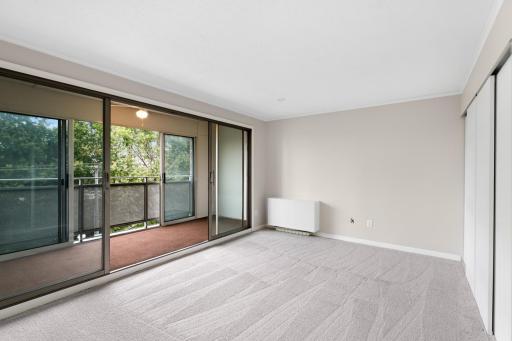 Spacious bedroom with neutral carpeting, abundant natural light, and direct access to the enclosed balcony.
