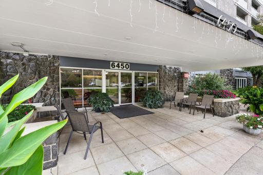 Covered front entrance with stone accents, seasonal plantings and outdoor seating, a welcoming spot to relax or greet guests