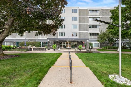 Welcome Home! Welcoming front entry with a covered drop-off, a landscaped walkway and a mature tree canopy