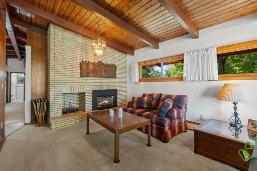 A full-height brick fireplace creates a cozy focal point and complements the home’s distinctive mid-century style