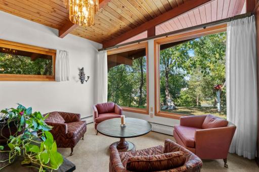 Oversized windows bring the outdoors in, filling this inviting sitting area with natural light and peaceful views of the trees
