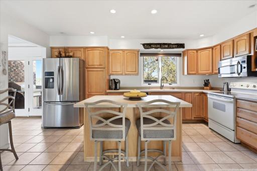 A beautifully appointed kitchen featuring a center island, Corian countertops, abundant cabinetry, and an additional snack bar for casual dining!