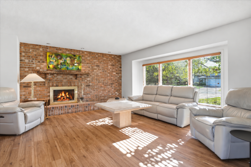 Rich hardwood floors and a striking wood-burning brick fireplace anchor this inviting living room with timeless warmth and character!