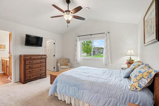 The primary bedroom includes a private 3/4 bathroom, a walk-in closet, a 10' vaulted ceiling, a ceiling fan & a newer large window to fill the room with natural light.