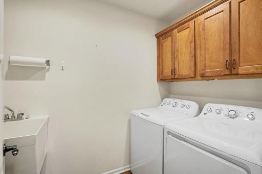 The laundry room includes GE washer and dryer, storage cabinets, luxury vinyl tile floor, and a utility sink.