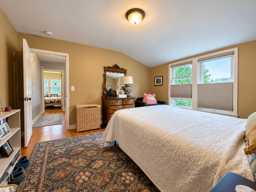 Space for bedside tables, your favorite dresser and books within reach. This reverse view shows a bedroom that accommodates everyday living, with paired windows and wood floors continuing into the hall.