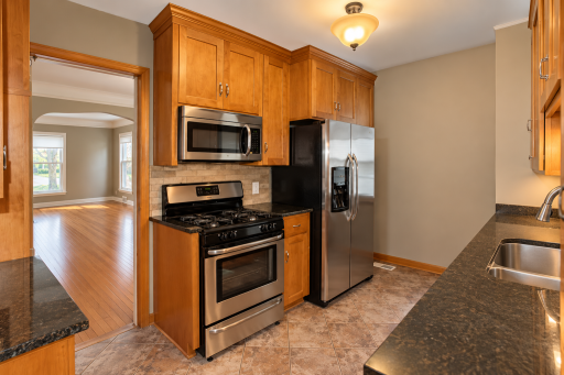A long counter provides generous prep space beside the sink. The gas range, stainless steel appliances and direct connection to the dining room make this kitchen practical for cooking and serving.