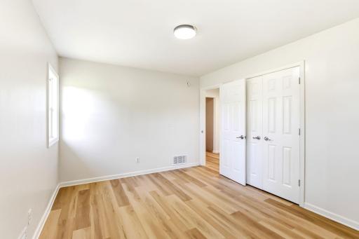 A second view of this bright bedroom highlights the generous double-door closet, clean modern finishes, and flexible layout with plenty of space for comfortable furniture placement.