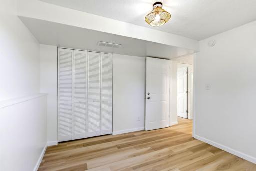 A second view of this bright bedroom highlights the generous double-door closet, clean modern finishes, and flexible layout with plenty of space for comfortable furniture placement.