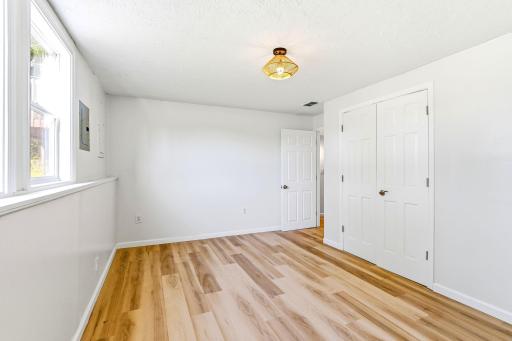 The fourth bedroom, conveniently located on the lower level, offers generous space, new flooring, fresh paint, a modern light fixture, and a large double-door closet.