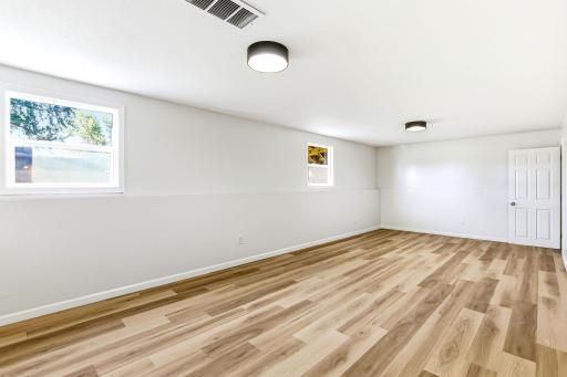 Spacious lower-level family room offering endless possibilities as a movie room, playroom, home gym, office, or entertainment space. New flooring, fresh paint, modern lighting, and multiple windows create a bright and comfortable place for everyone.