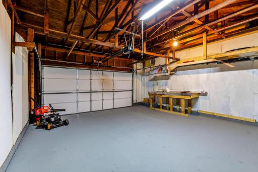 Spacious attached two-car garage offering more than just parking, with a built-in workbench, overhead storage, bright lighting, and plenty of room for tools, equipment, and seasonal items, an excellent space for projects, hobbies, or organization