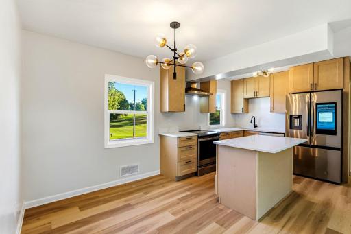 The beautifully renovated kitchen features high-end stainless-steel appliances, including a smart refrigerator, a spacious center island, and a dedicated breakfast area, which is perfect for enjoying casual meals with a view of the backyard.