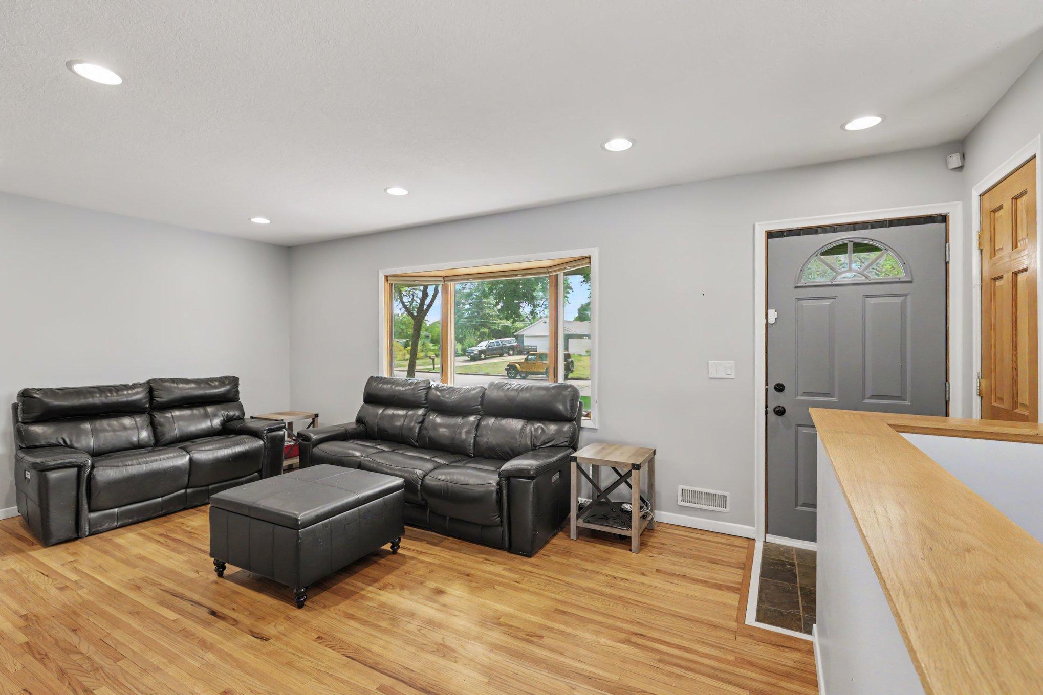 The spacious living room features beautiful hardwood floors, recessed lights, a large bay window, and a convenient coat closet.