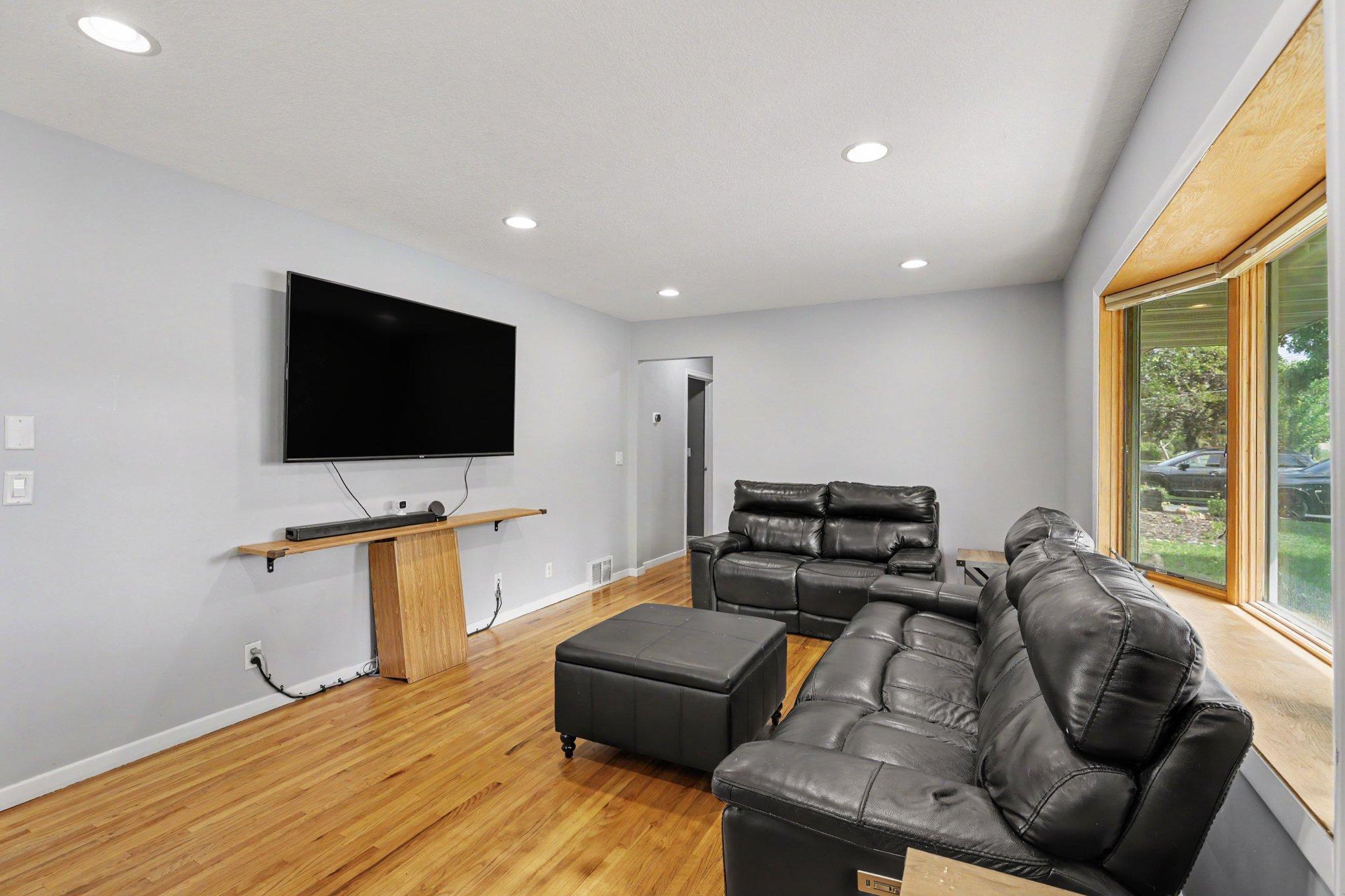 Another view of the spacious living room. The room is bathed in natural light from the large front bay window.