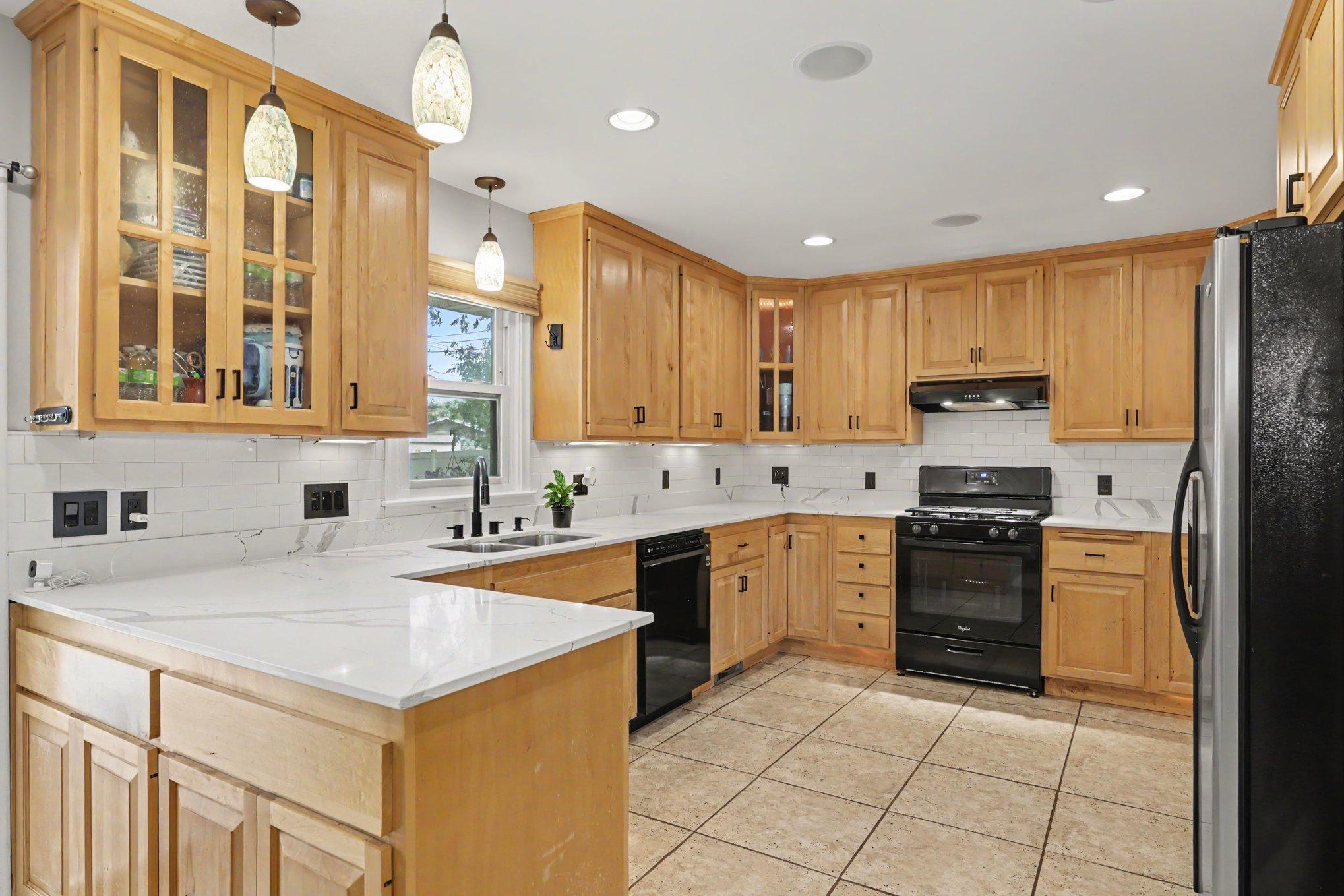 The side door brings you right into the beautiful, refreshed kitchen. It features refinished maple cabinets, quartz countertops, a tile backsplash, heated ceramic tile floors, a new sink with disposal and faucet, and new cabinet pulls.
