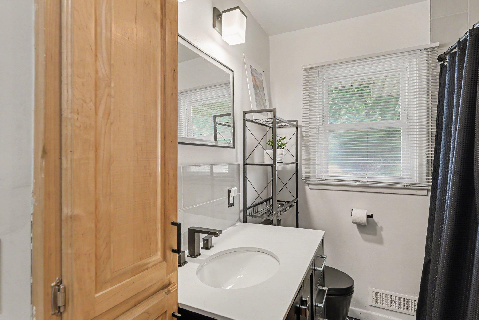 The main level features a full bathroom equipped with heated ceramic tile flooring, a comfort-height vanity with storage, a bidet, a dual-flush toilet, a linen closet, and a tub with a tile surround.
