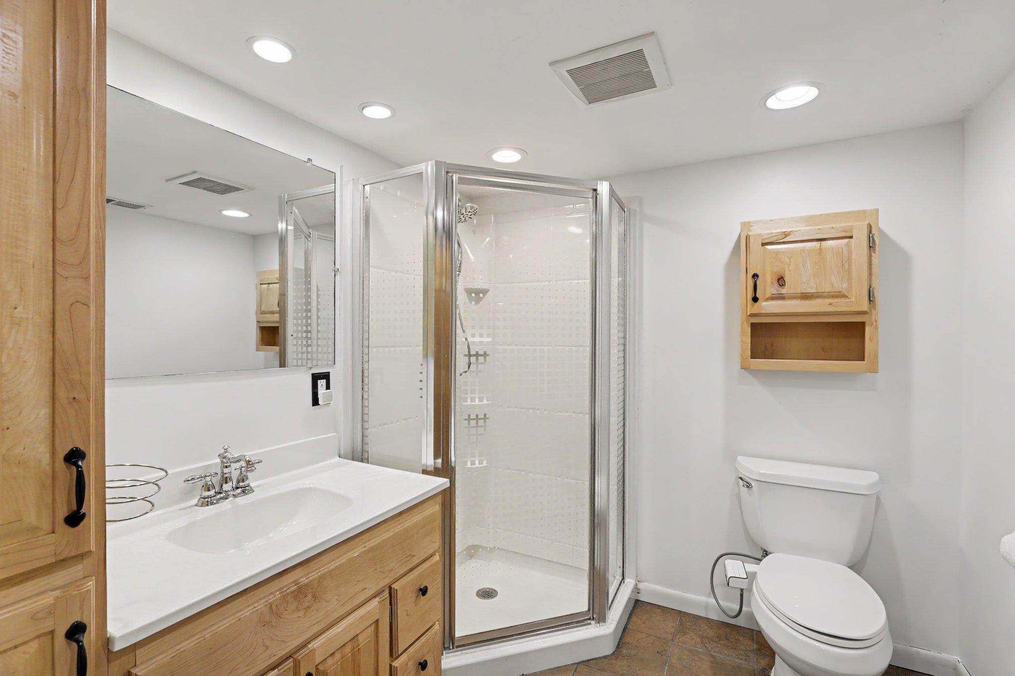 The lower level 3/4 bathroom includes heated floors, a vanity with storage and a linen cabinet, and recessed lights.
