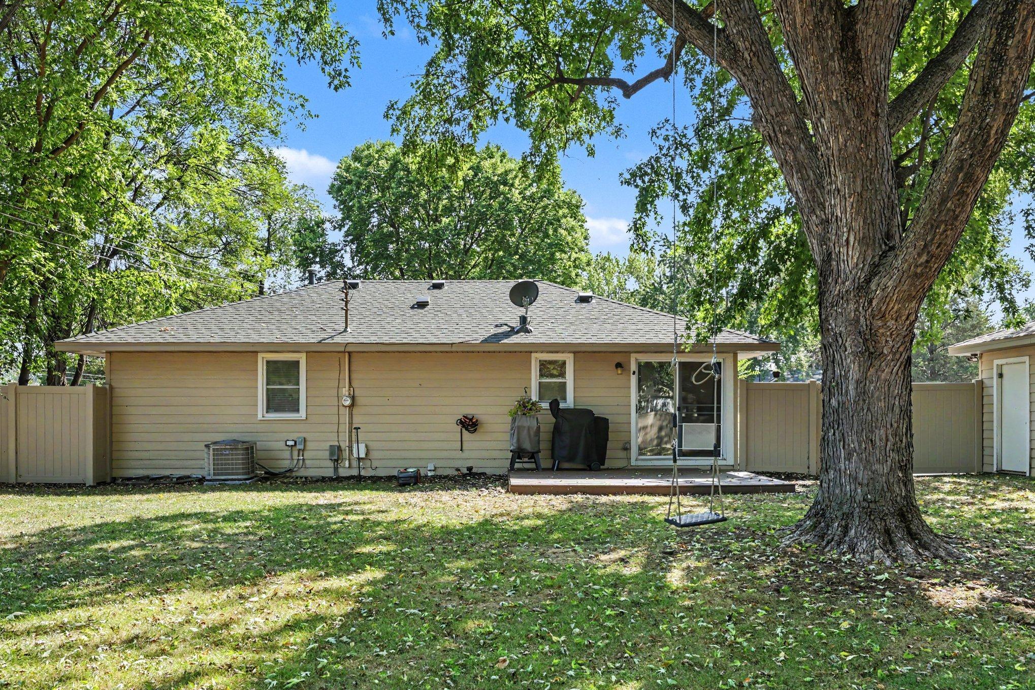 The spacious private backyard is shaded by mature trees. The house has a new roof from 2021, vinyl siding, and a vinyl privacy fence installed in 2026.