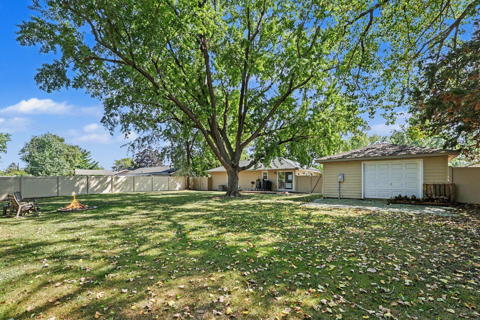 This view features the garage's rear pull-through door, the firepit area, and the newly installed vinyl privacy fence.