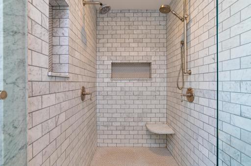 Dual shower heads and stunning marble tile it in the oversized primary shower!