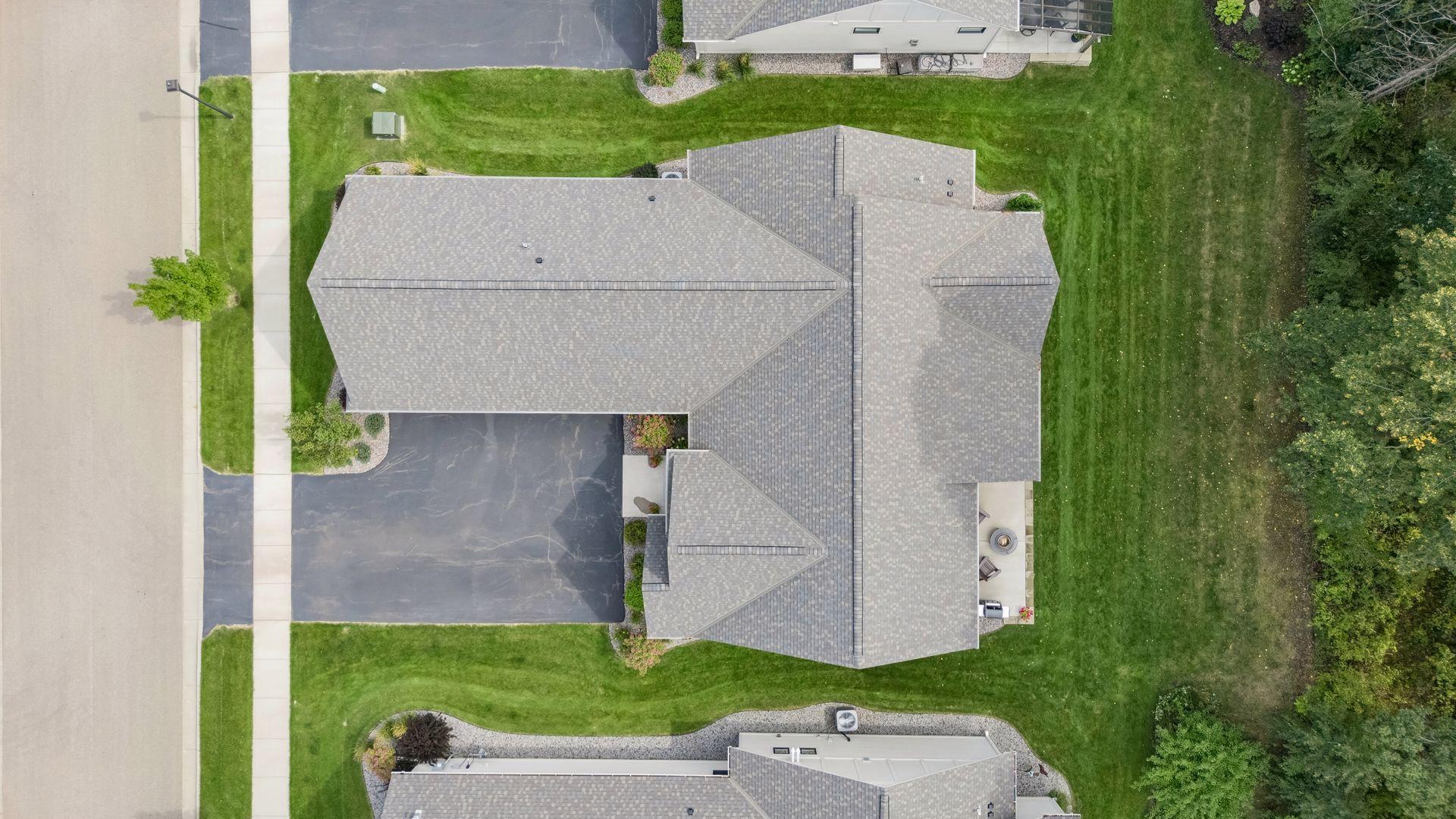A bird's-eye view showcases the home, spacious three-car garage, beautiful landscaping, and peaceful setting within Park Place Village.