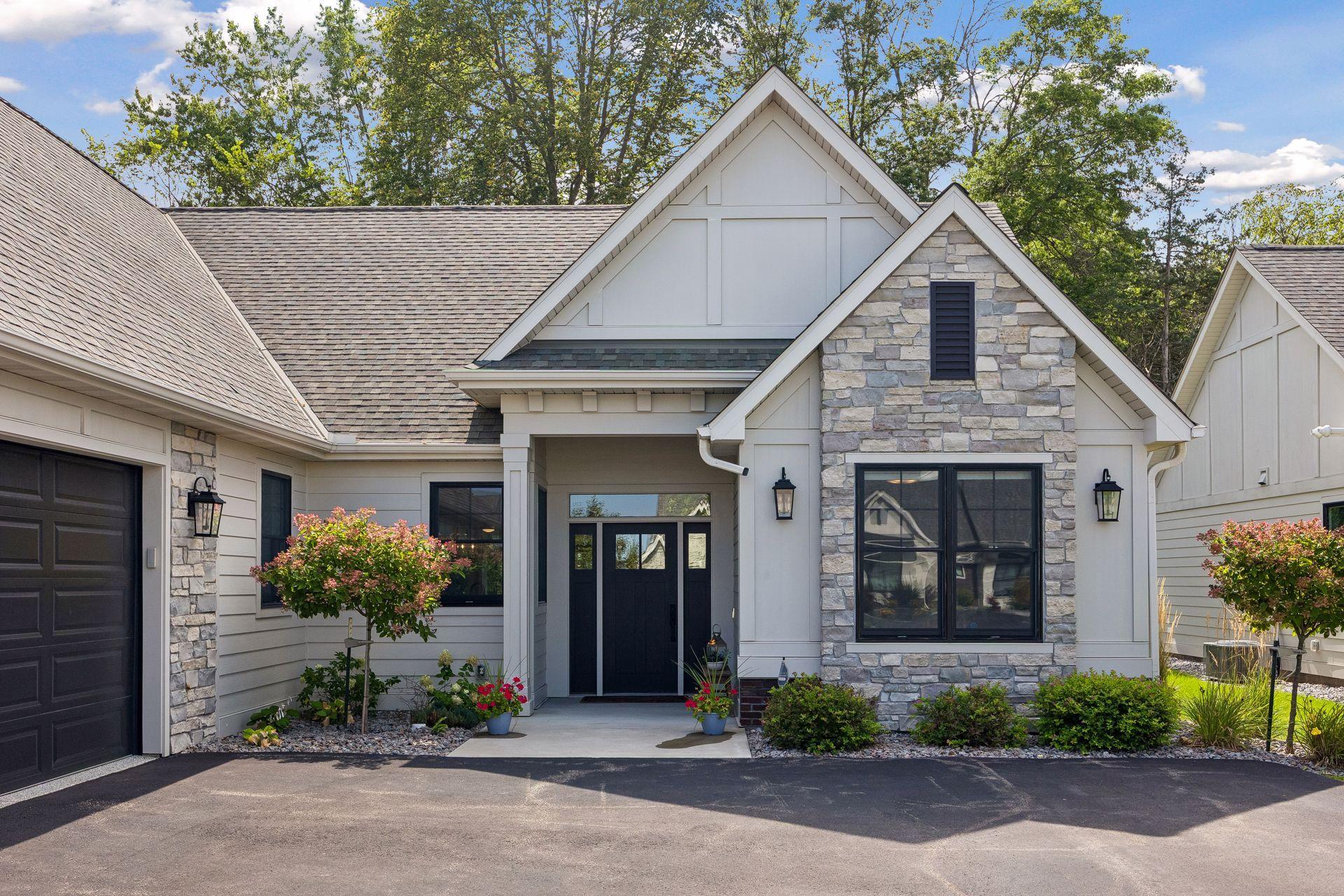 A welcoming front entry surrounded by beautiful landscaping, striking black windows, and thoughtfully selected exterior finishes.