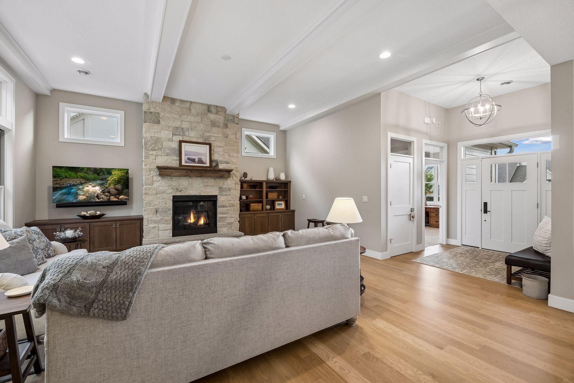 The great room is a showstopper with white oak floors, beautiful ceiling details, and a floor-to-ceiling stone gas fireplace anchoring the space.