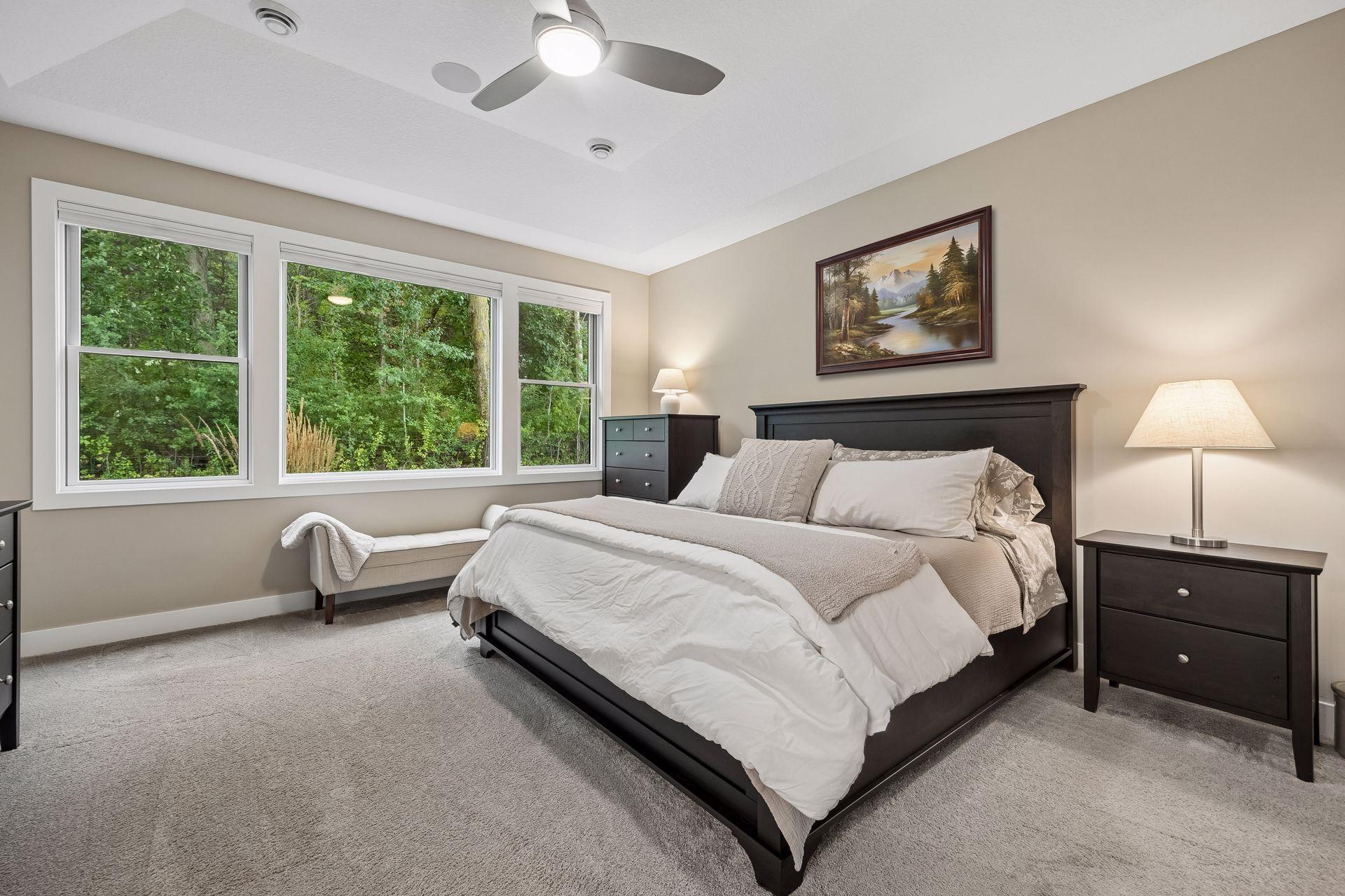 The spacious primary bedroom features a beautiful tray ceiling and peaceful views of the surrounding trees.
