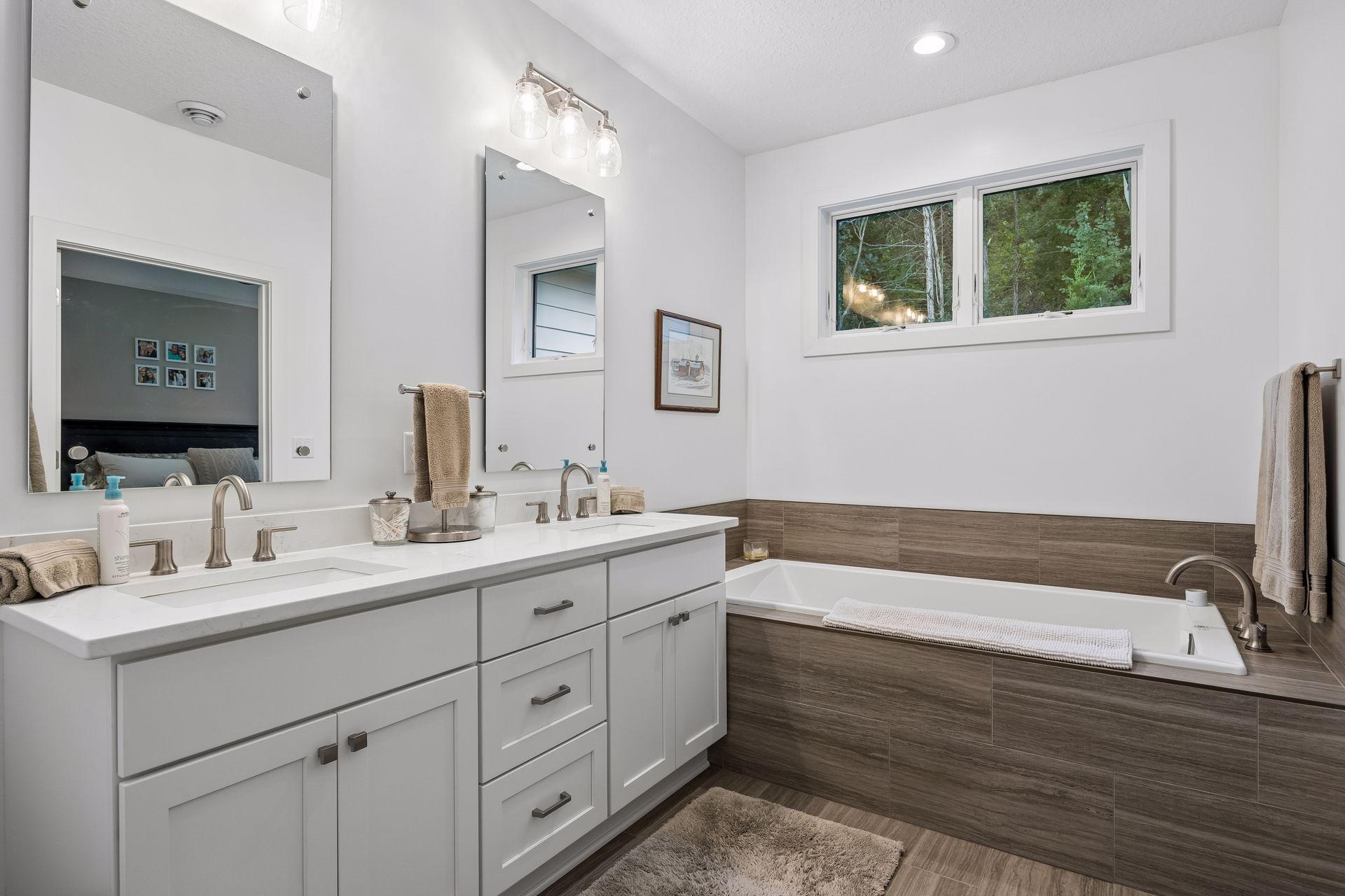 A perfectly placed window above the soaking tub brings natural light into the primary bathroom while maintaining a relaxing feel.