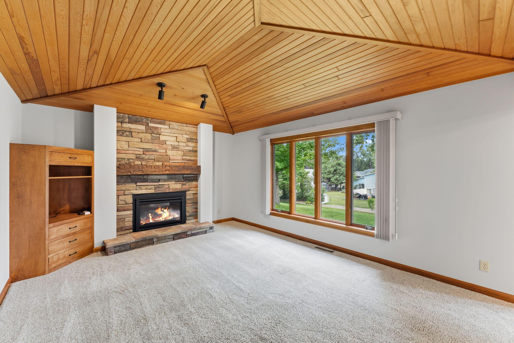 Cozy family room showing off the tongue & groove ceiling, a beautiful stone gas-fireplace + mantle and warm up those chilly evenings!!