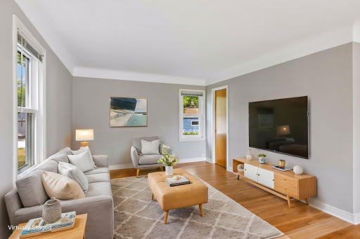Virtually staged living room with original hardwood floors, fresh paint and coved ceilings.