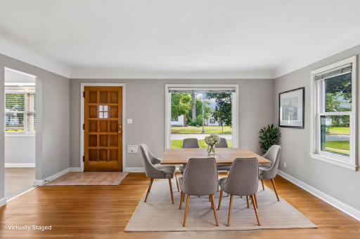 Virtually staged informal dining room with original hardwood floors, freshly painted, coved ceilings and a large picture window flooding the room with morning light.
