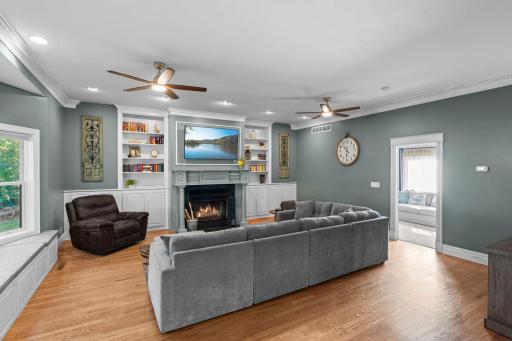 A family room off the kitchen featuring built in bookcases and a wood burning fireplace.