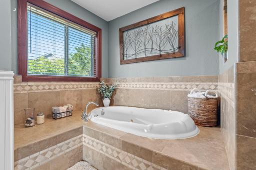 This bathroom has a soaking tub and a walk-in shower. It opens to the bedroom and into the hallway.