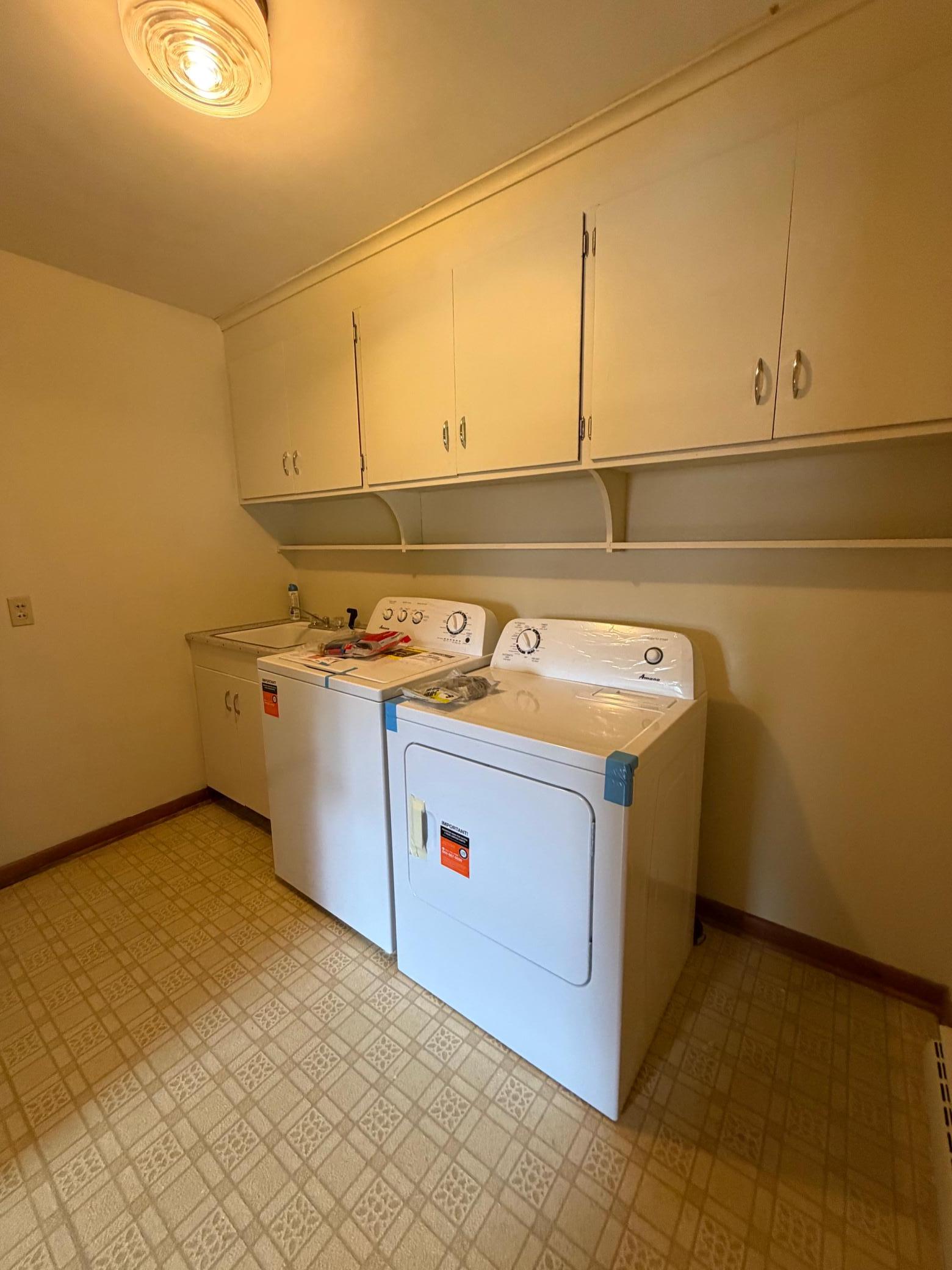 brand new washer and dryer in laundry room just off the garage, with wash sink